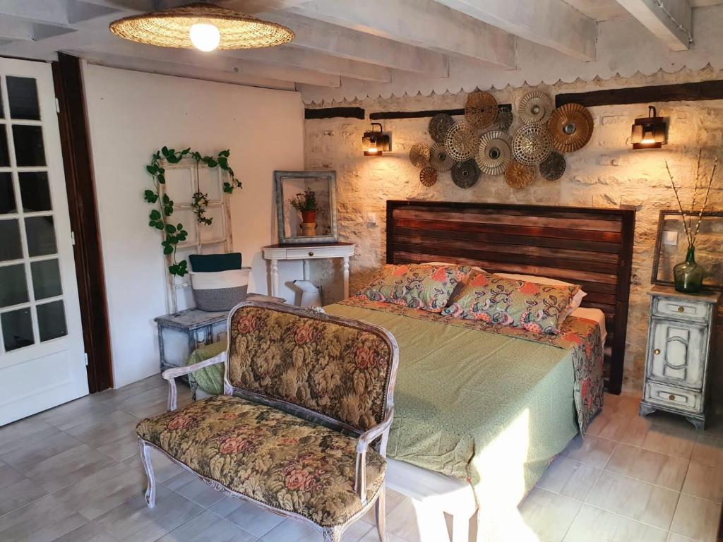 a bedroom with a bed and a chair at La Fontenelle Meublé in Sainte-Sévère