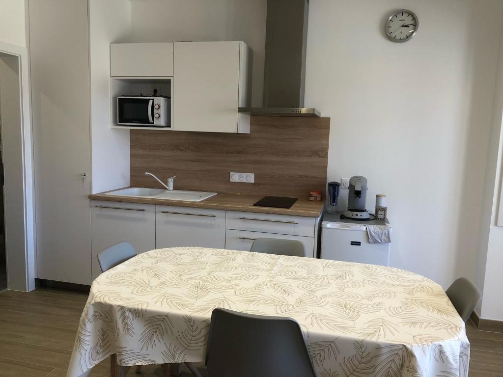 a kitchen with a table with chairs and a microwave at Sollaris Appartement 1ère étage à 11km de Europa-Park in Friesenheim