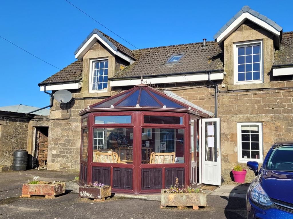 a red building in front of a house at Blairmains Guest House in Kirk of Shotts