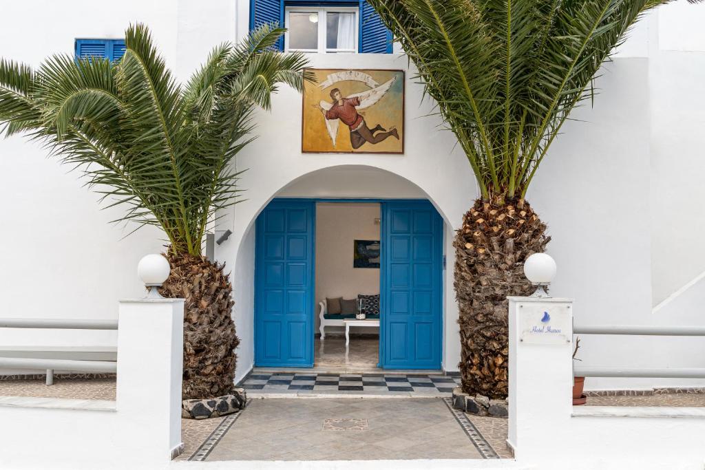 a house with two palm trees in front of a blue door at Ikaros in Karterados