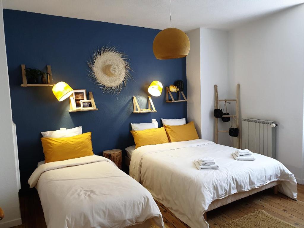 two beds in a room with blue walls and yellow pillows at Chambres d'Hôtes et Gîtes- L'Abri sous Roche in Tautavel