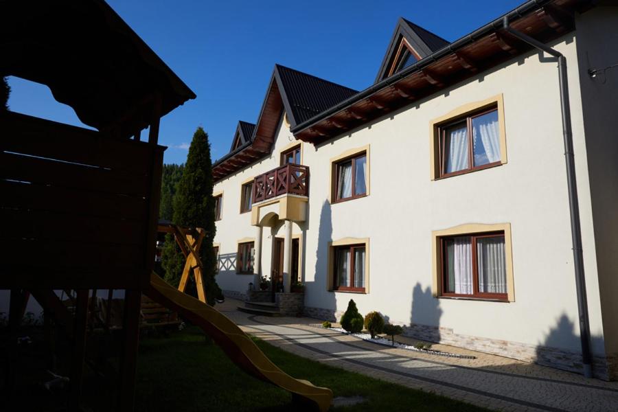 a large white building with a slide in front of it at Łapszańska Ostoja in Łapsze Niżne