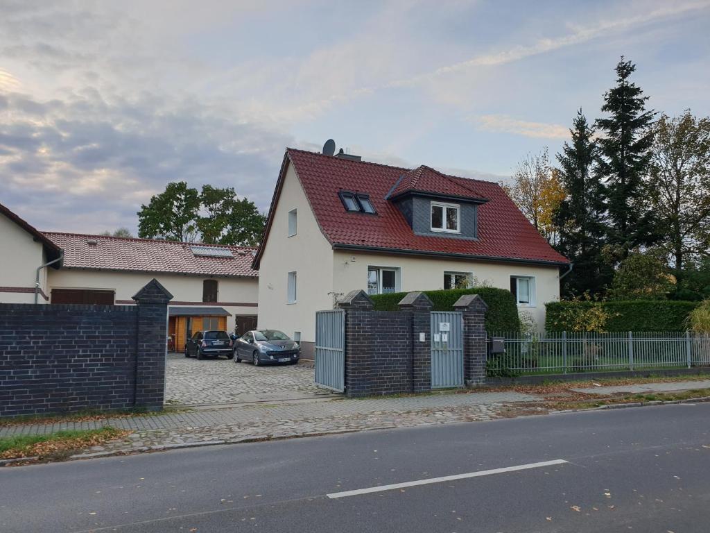 ein weißes Haus mit rotem Dach und einem Parkplatz in der Unterkunft In the House in Schönfließ