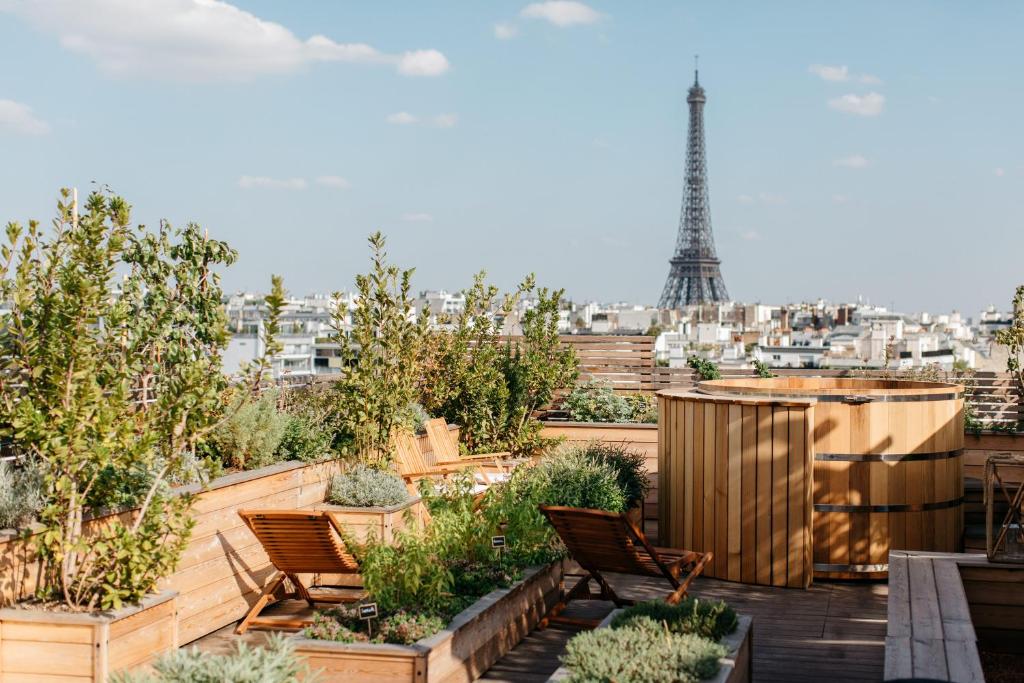 um jardim no último piso com cadeiras e a Torre Eiffel em Brach Paris - Evok Collection em Paris