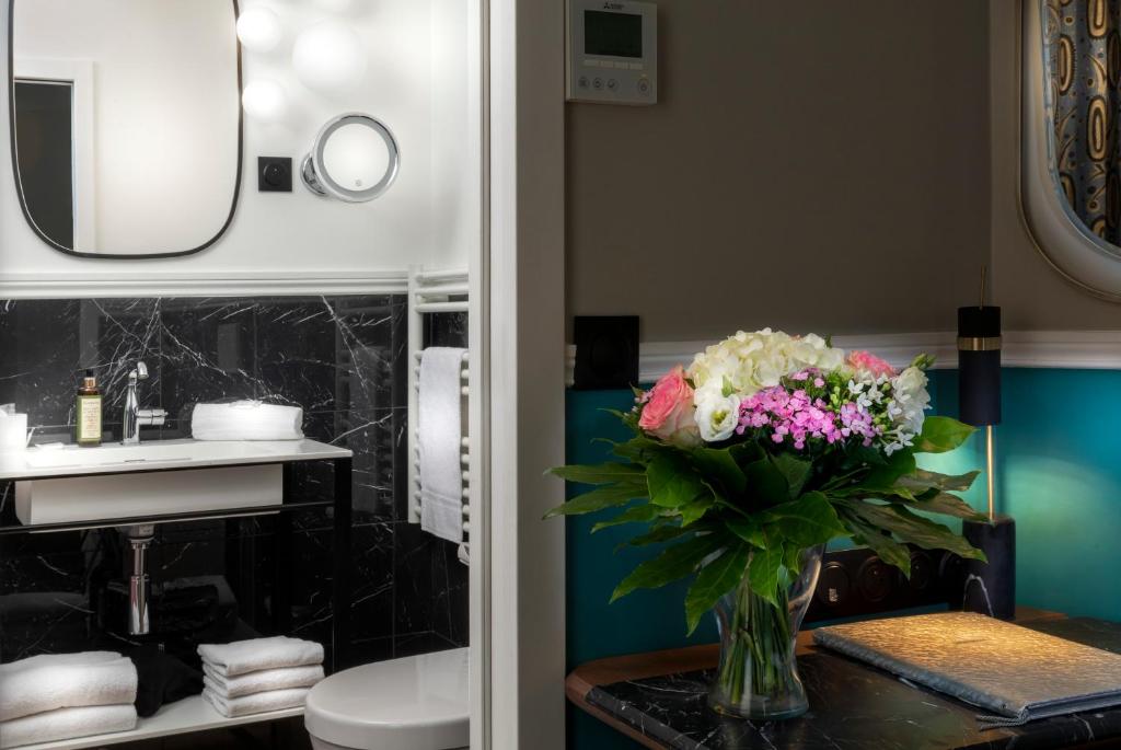 a vase of flowers on a table in a bathroom at Hotel Elysa-Luxembourg in Paris