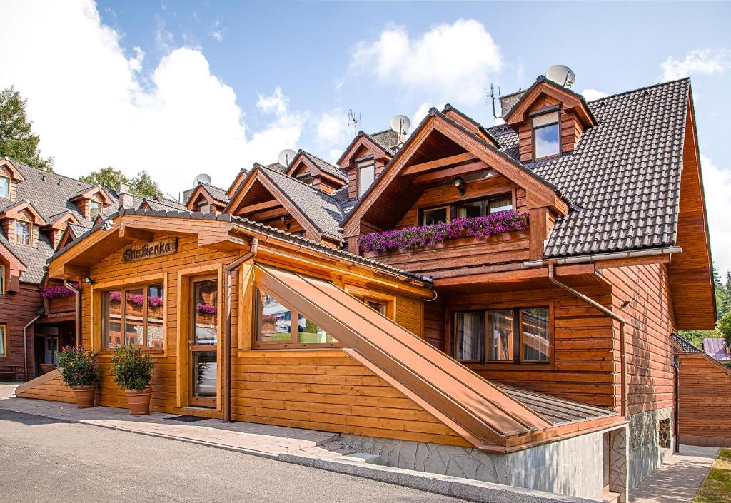 a wooden house with a gambrel roof at Penzion Snezienka in Tatranská Lomnica