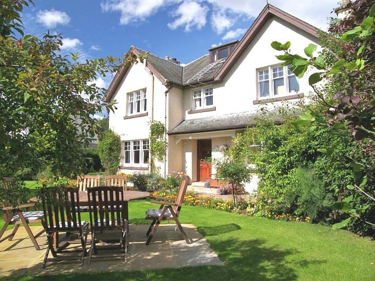 a house with chairs and a table in the yard at Dalgreine Guest House in Blair Atholl