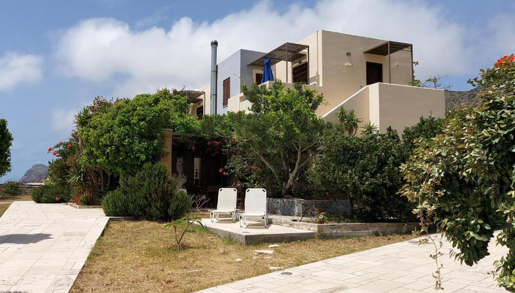 una casa con dos sillas blancas delante en Doma Apartments, en Falasarna