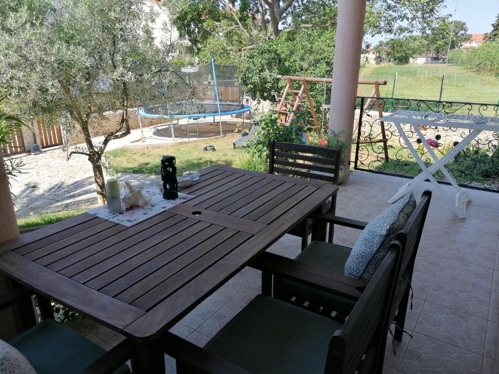 een houten tafel en stoelen op een patio met een speeltuin bij Apartman Rafael in Medulin