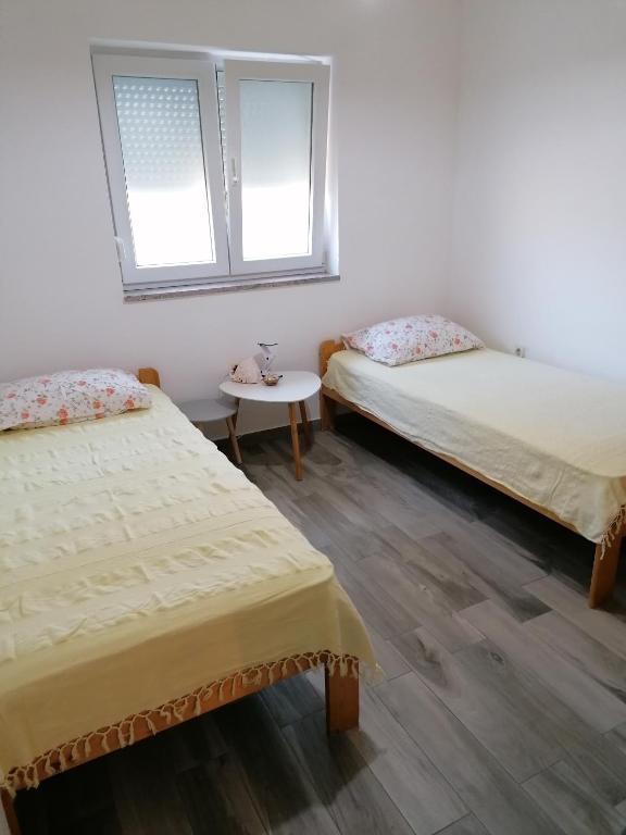 Pokój z 2 łóżkami i stołem oraz 2 oknami w obiekcie Apartman Rafael w Medulinie