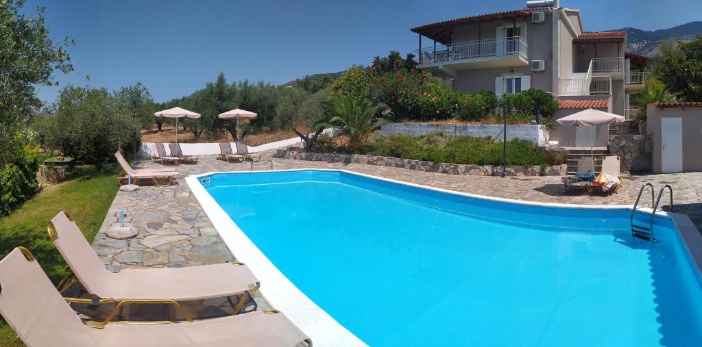 a swimming pool with chairs and a house at Manolia Studios in Trapezaki