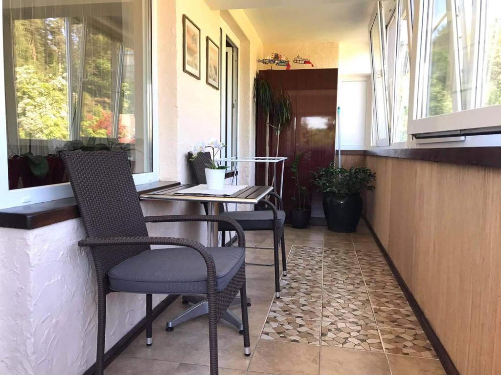 a porch with two chairs and a table and windows at Roberto apartamentas Juodkrantėje in Juodkrantė