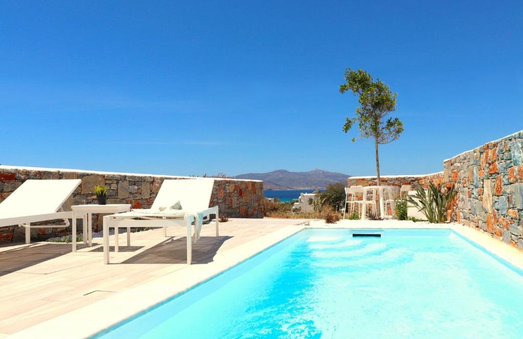 una piscina con tavolo e sedie accanto a un edificio di The Nine Graces - Agia Anna - Option With private pool or hot tub ad Agia Anna Naxos