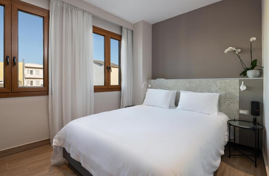 a bedroom with a large white bed and a window at Al Daliani Minaret Rooms in Chania