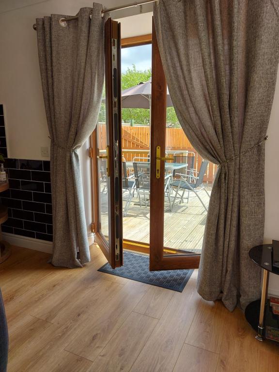 a door with curtains open to a patio with a table at Bonnie View Fort William Cottage in Fort William