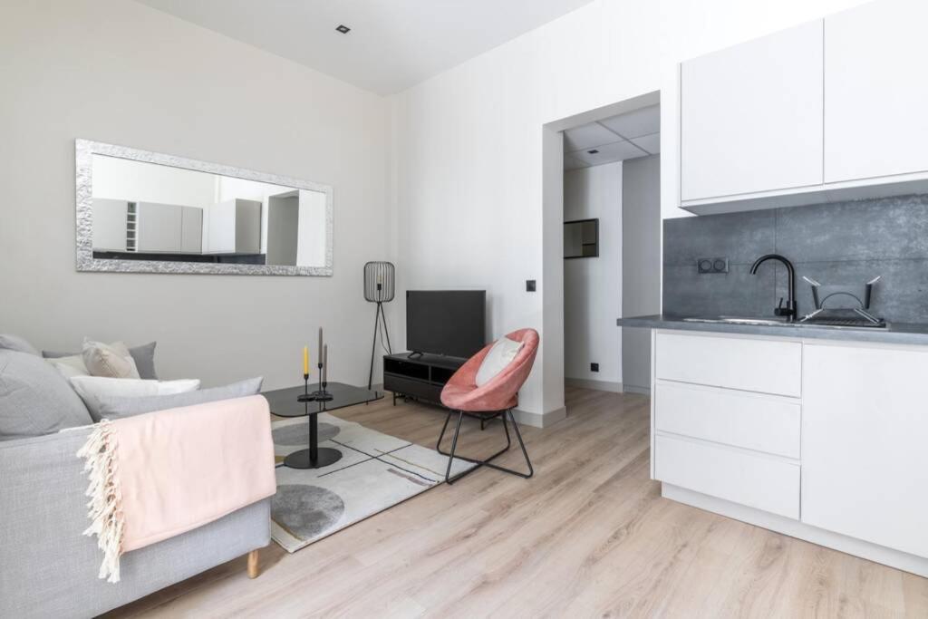 cocina y sala de estar con sofá y lavamanos en HSH Volney-Opéra Appartement Design 4P-1BR, en París