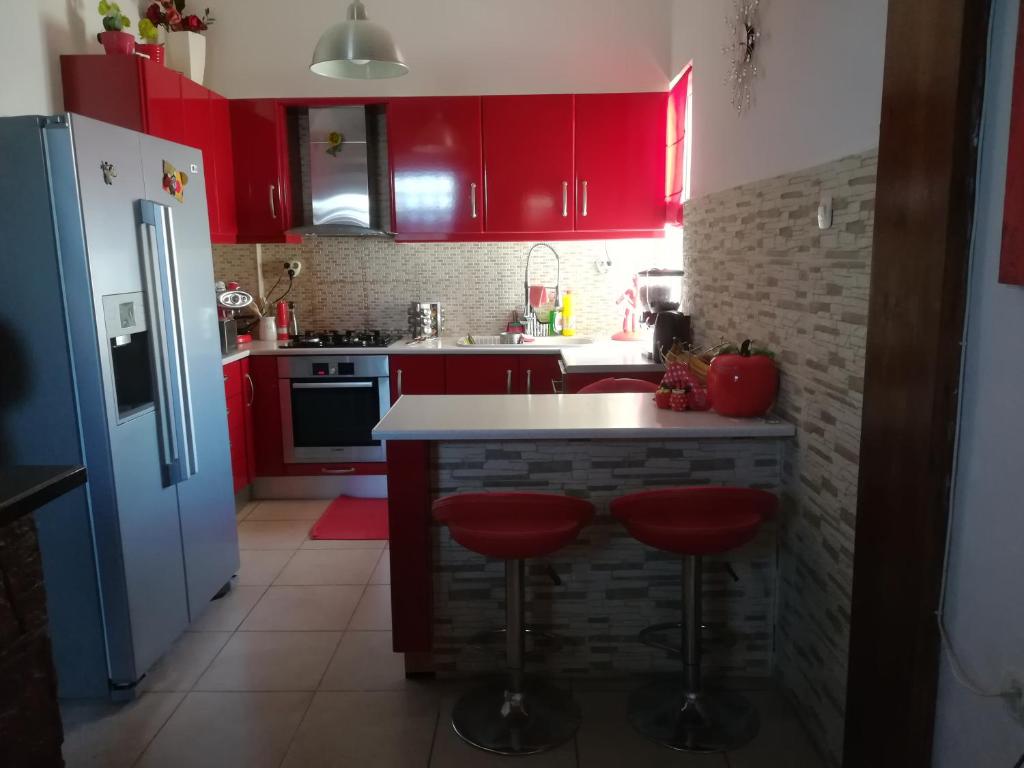 uma cozinha com armários vermelhos e bancos de bar vermelhos em Sitiahome em Sitia