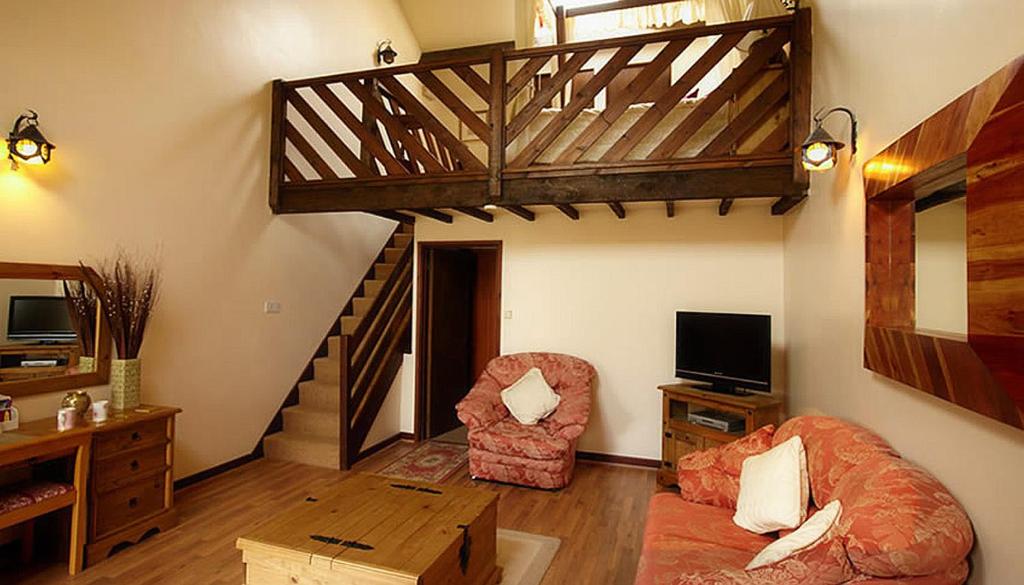 ein Wohnzimmer mit einer Treppe, einem Sofa und einem Stuhl in der Unterkunft Miltons Country Lodge in Langford