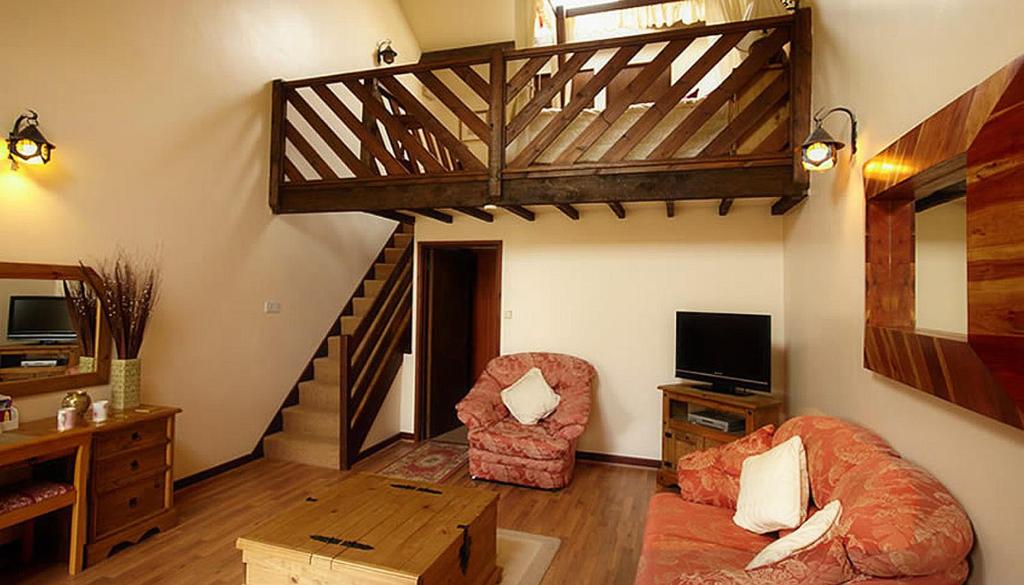 a living room with a staircase and a couch and chair at Miltons Country Lodge in Langford