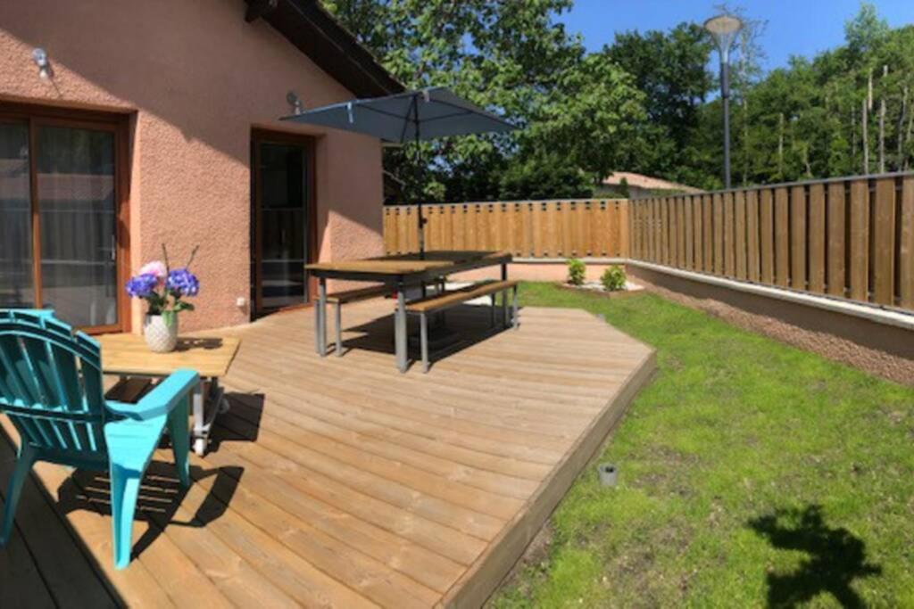 una terraza de madera con mesa de picnic y banco en LE LOGIS DES JALLES en Saint-Médard-en-Jalles