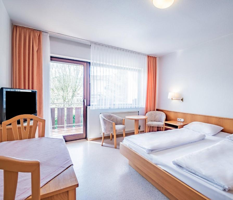 a hotel room with two beds and a table and chairs at Aparthotel Panorama in Bad Soden-Salmünster
