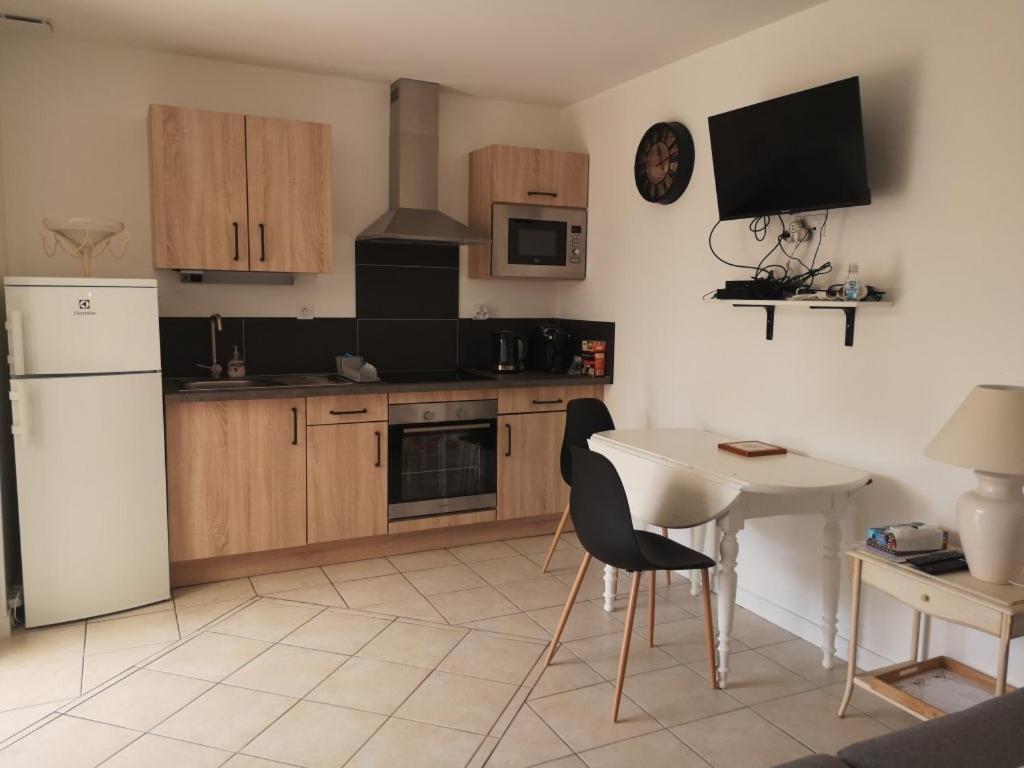 a kitchen with a white table and a white refrigerator at Appartement 2 pièces avec terrasse proche mer et commerces in Ouistreham