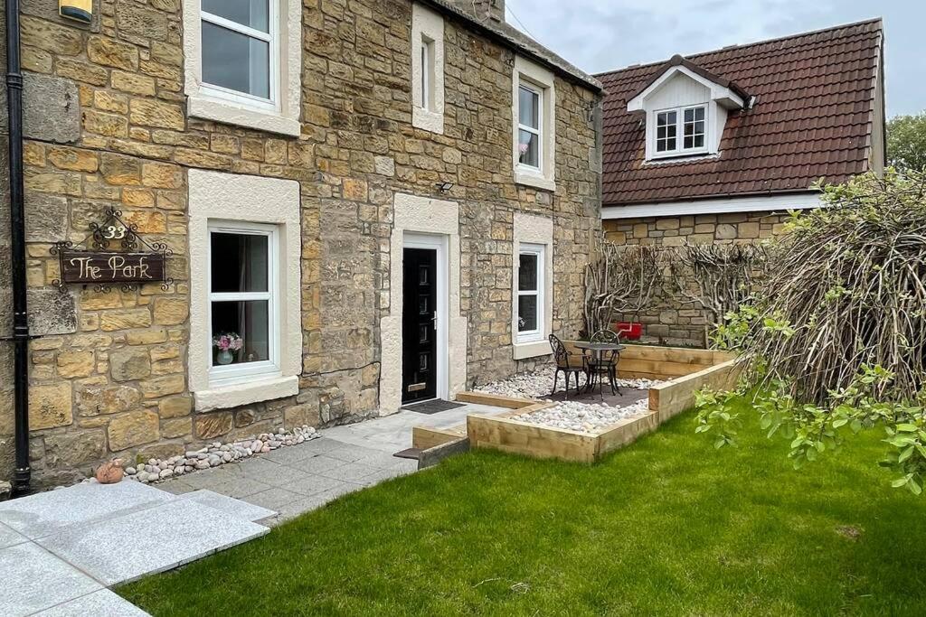 a stone house with a grass yard in front of it at Castle View House in Dalkeith