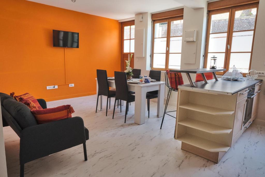 a living room with orange walls and a table and chairs at AU COCON CASSELOIS in Cassel