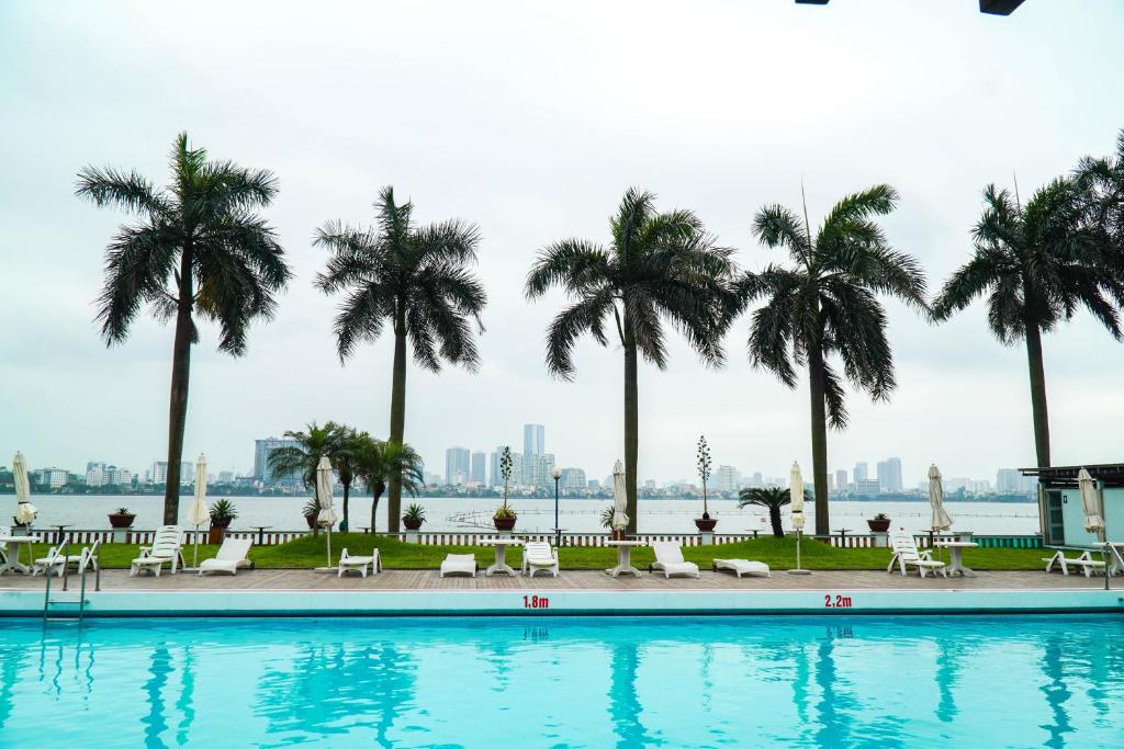 een zwembad met palmbomen op de achtergrond bij Thang Loi Hotel in Hanoi