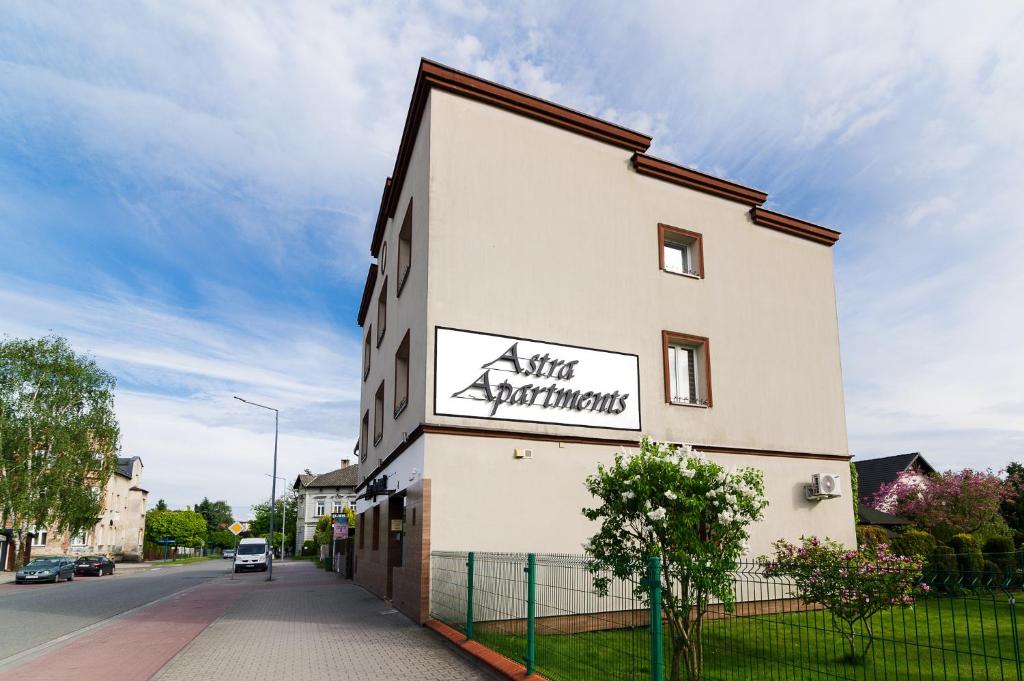 a white building with a sign on the side of it at Astra Apartments in Oświęcim