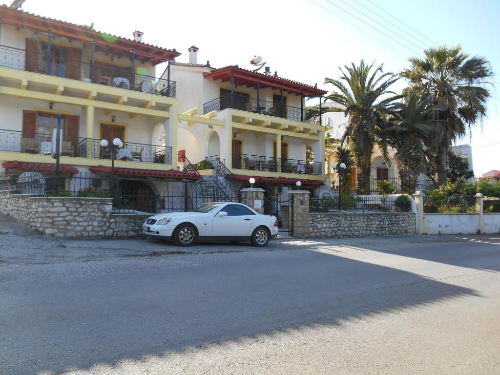 un coche blanco estacionado frente a un edificio en Melios Rooms, en Petalidi
