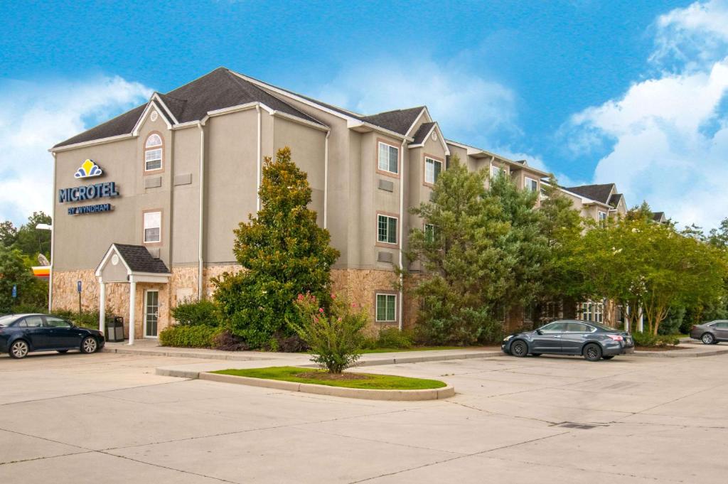 a hotel with cars parked in a parking lot at Microtel Inn & Suites by Wyndham Pearl River/Slidell in Pearl River