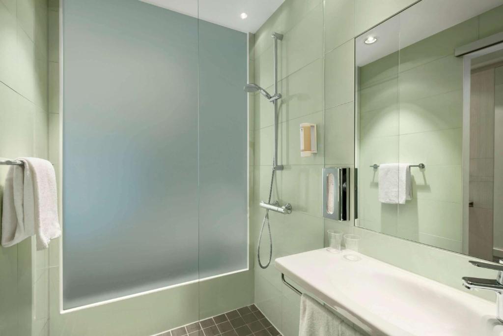 a bathroom with a shower and a sink and a mirror at Super 8 by Wyndham Munich City North in Munich