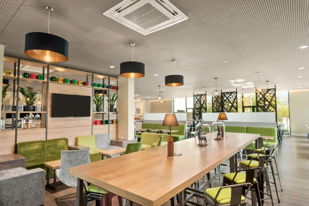 a restaurant with a large wooden table and chairs at Super 8 by Wyndham Munich City North in Munich