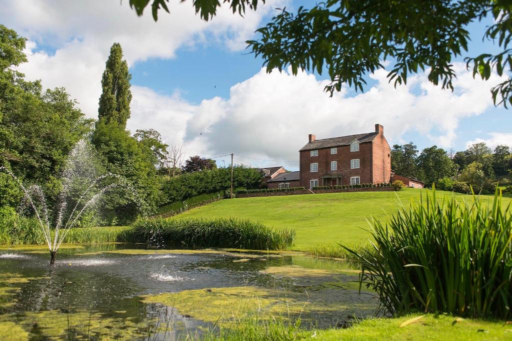 a house and a pond in front of a house at Bettws Hall Accommodation in Newtown