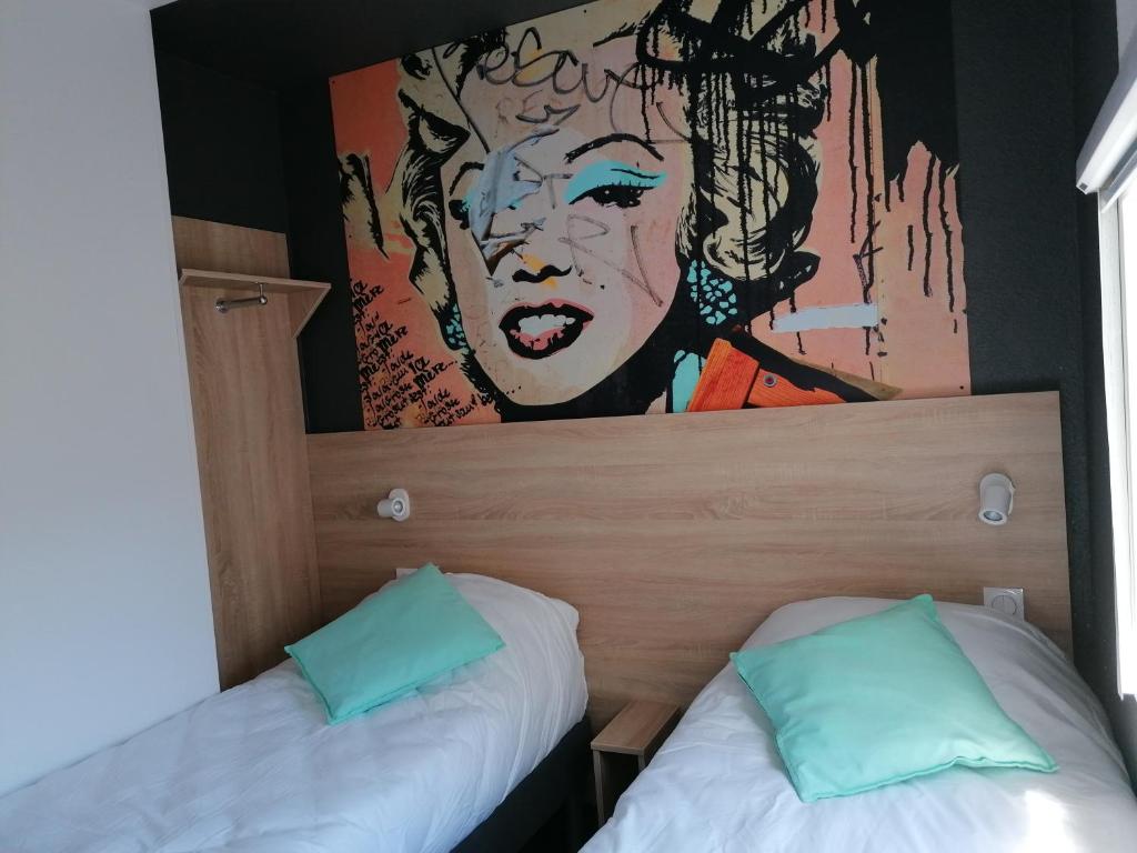 2 Betten in einem Zimmer mit Wandgemälde in der Unterkunft Kyriad Direct Orleans - Olivet - La Source in Olivet