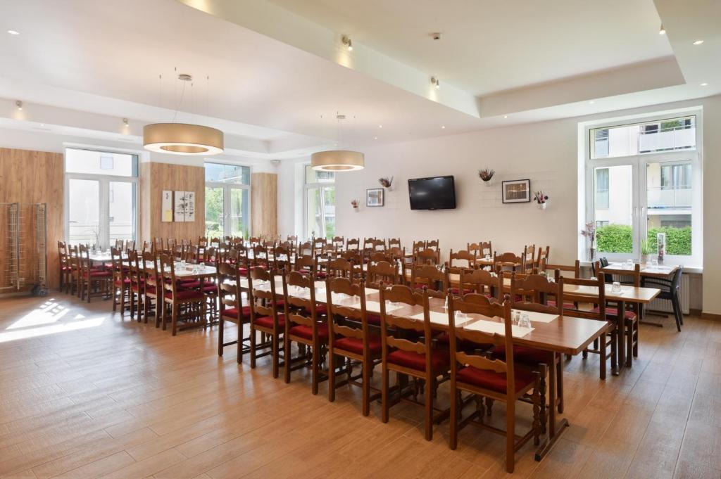 a large room with tables and chairs and a flat screen tv at Hotel Central in Engelberg