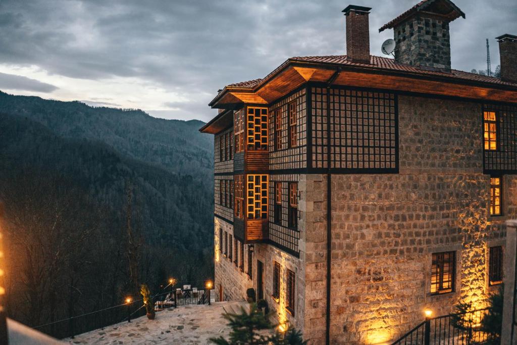 DUDİ KONAK HOTEL في ريزي: مبنى شبابيكه على جانب جبل