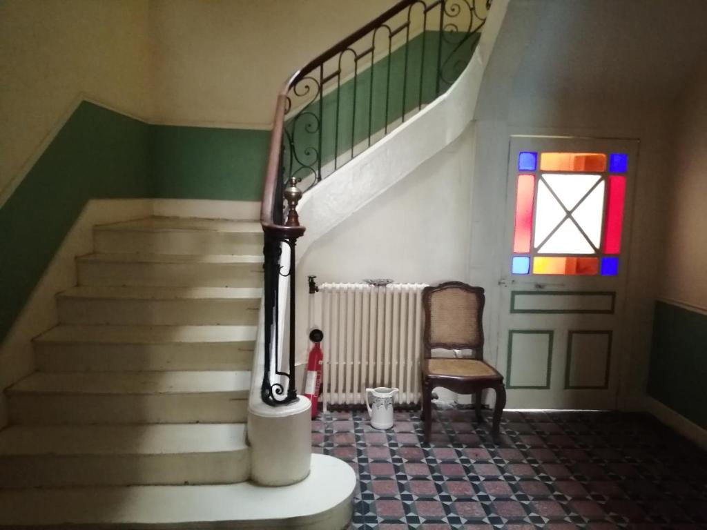 un escalier avec une chaise et un vitrail dans l'établissement MAISON ALBA LA SOURCE, à Mazamet