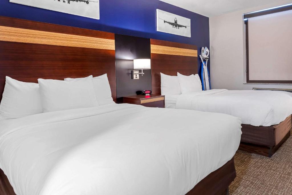 a hotel room with two beds and a television at Avion Inn Near LGA Airport, Ascend Hotel Collection in Queens