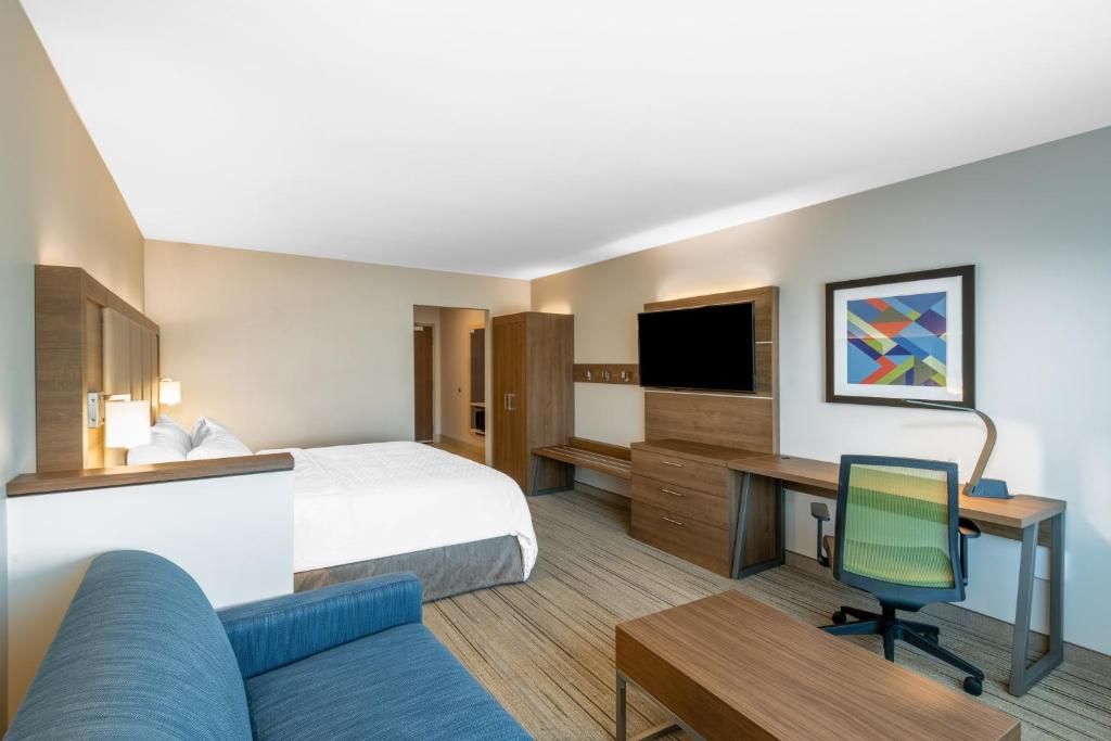 フェニックスにあるHoliday Inn Express & Suites - Phoenix - Airport North by IHGのベッドと机とテレビがあるホテルの部屋