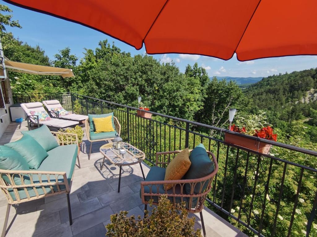 einen Balkon mit Stühlen, Tischen und einem Sonnenschirm in der Unterkunft Apartment Franko - Hum in Hum