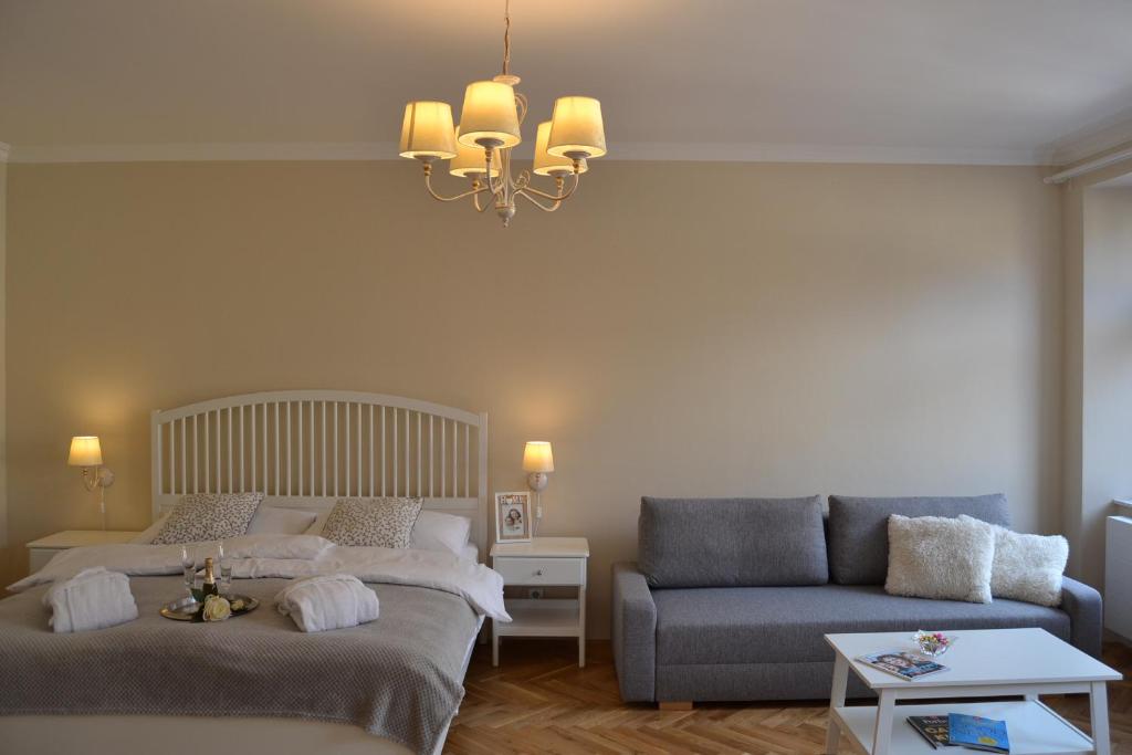 a bedroom with two beds and a couch and a chandelier at Rezidence U prince č. 2 in Jičín