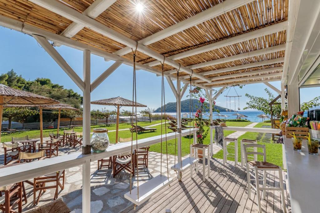 a patio with tables and chairs and a view of the water at Milia Beach Apartments in Paralia Milia