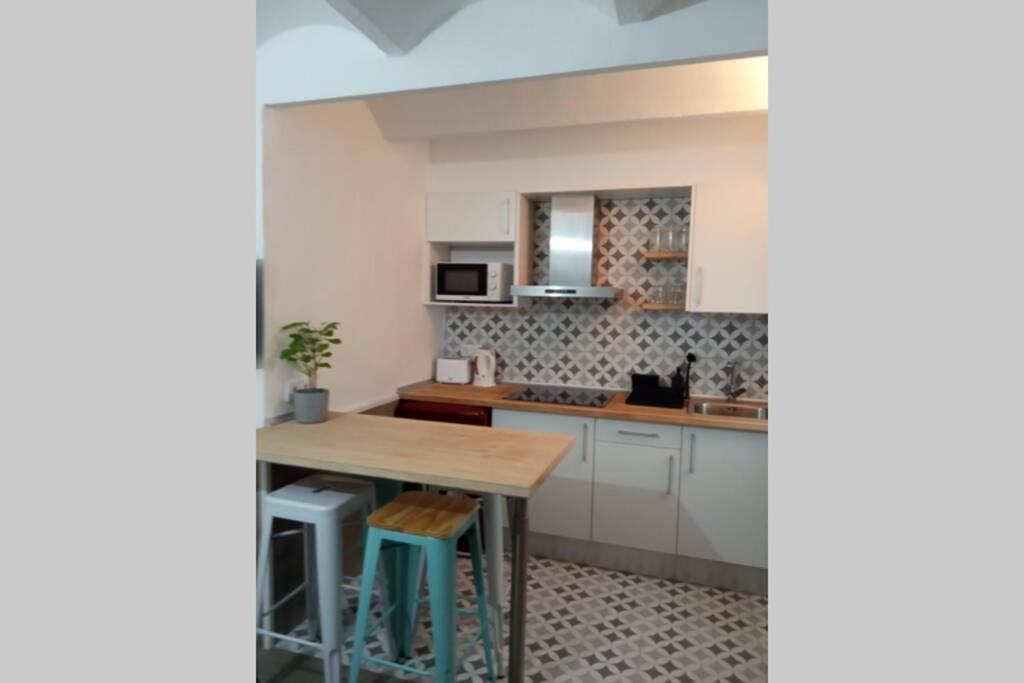 uma cozinha com uma mesa de madeira e uma bancada em M2 Cool apartment next to metro. 15m to center em Esplugues de Llobregat