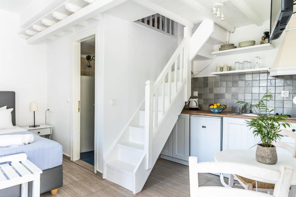a white apartment with a staircase and a kitchen at Milia Beach Apartments in Paralia Milia