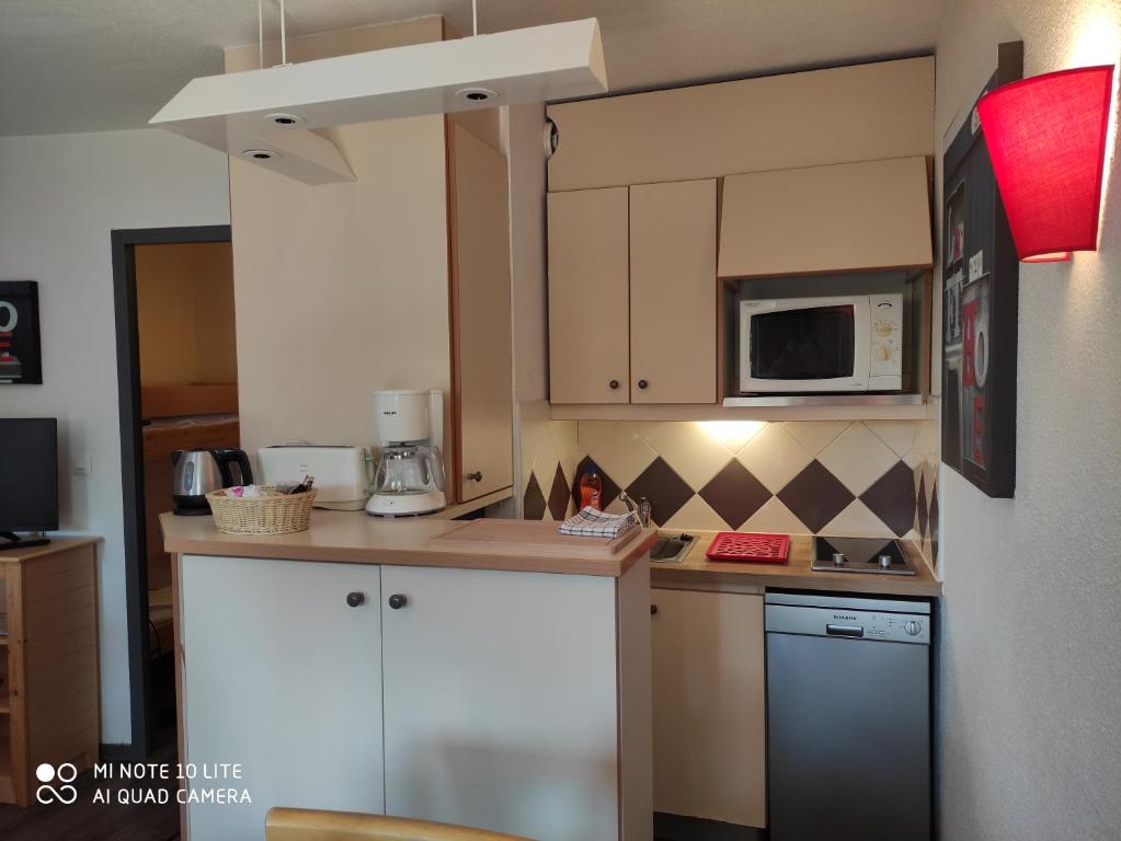 una pequeña cocina con armarios blancos y microondas en Appartement Les Palmiers, en Niza