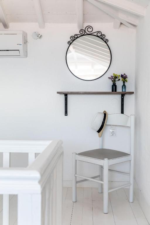 a white bathroom with a mirror and a stool at Milia Beach Apartments in Paralia Milia