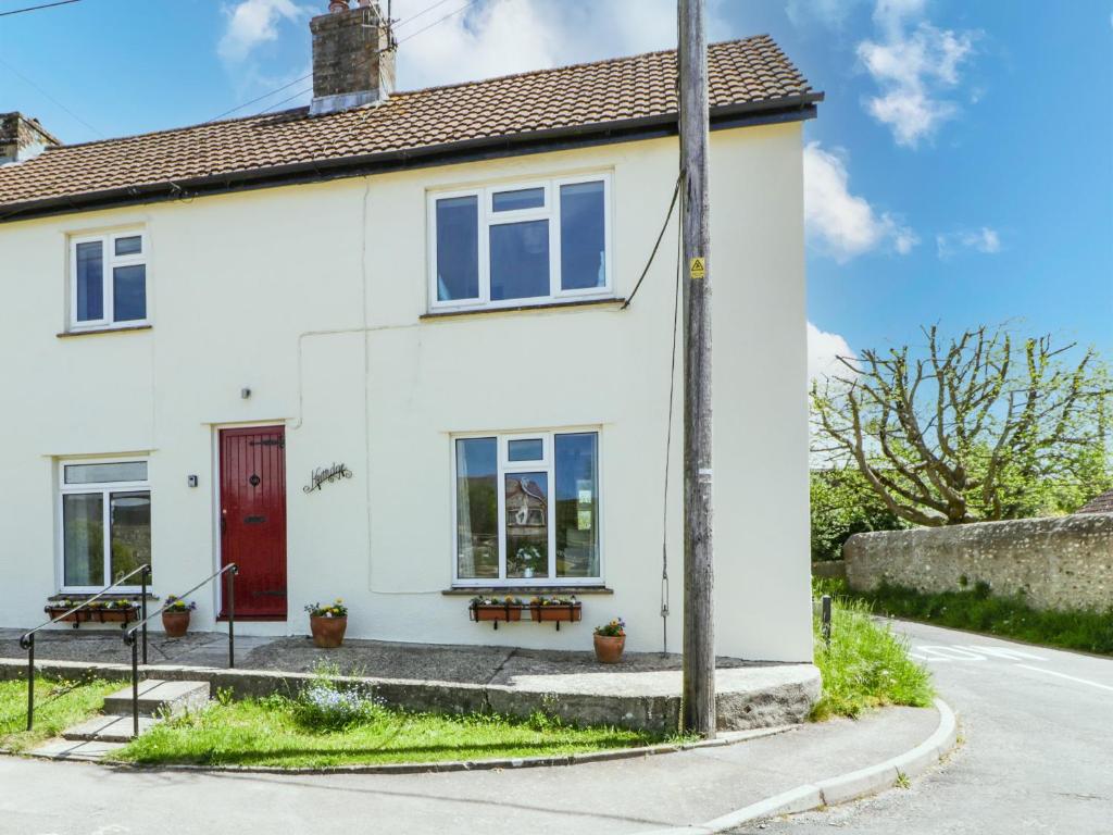 uma casa branca com uma porta vermelha numa rua em Kerridge em Dorchester