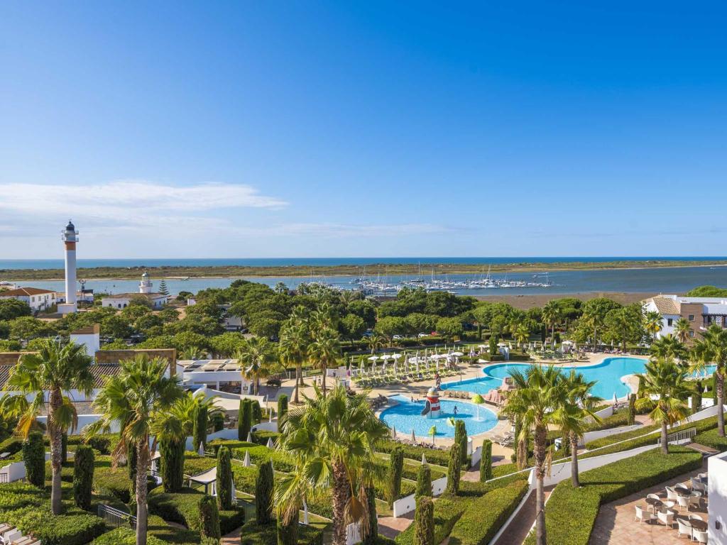 an aerial view of a resort with a pool and a lighthouse at Hotel Fuerte El Rompido in El Rompido